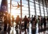 Passengers queue inside an airport terminal at sunset