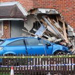Blue car crashed into brick house wall