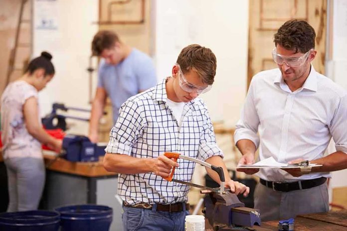 shutterstock_213304465 Students using tools in a workshop with instructor supervising