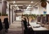 Open-plan office with empty desks and plants along partitions