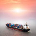 Container ship at sea under a hazy sunset