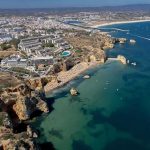 Coastal city with cliffs, beaches, and boats on turquoise water