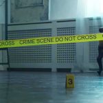Crime scene tape across a room with evidence marker on floor