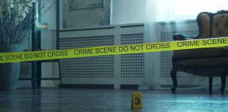 Crime scene tape across a room with evidence marker on floor