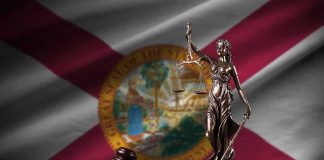 Lady Justice statue with gavel and book before Florida state flag
