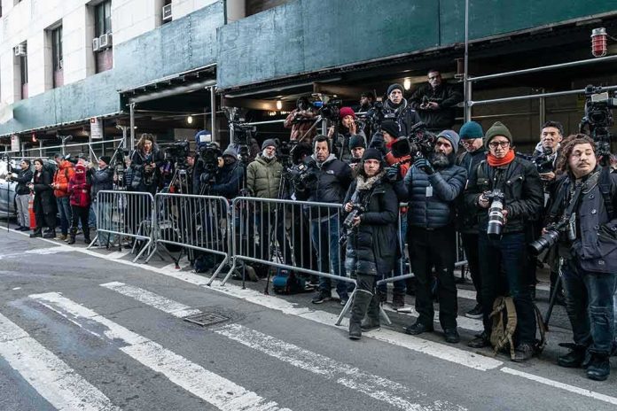 crowd of photographers behind barricades on a city street