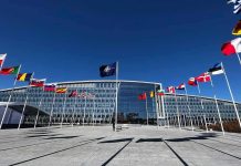 NATO headquarters with member flags in front under a clear blue sky
