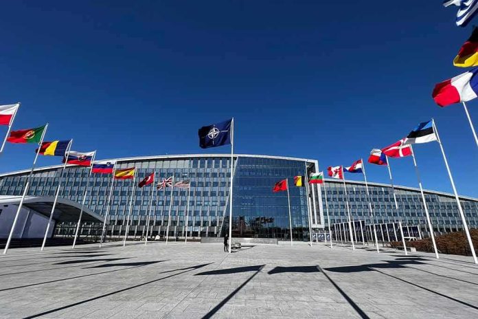 NATO headquarters with member flags in front under a clear blue sky