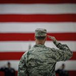 Soldier saluting before a large American flag