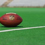 American football on a green field near a white line