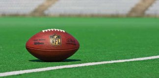 First NFL Interception Turns Into Sideline Drama American football on a green field near a white line
