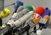 A collection of various microphones arranged for a press conference