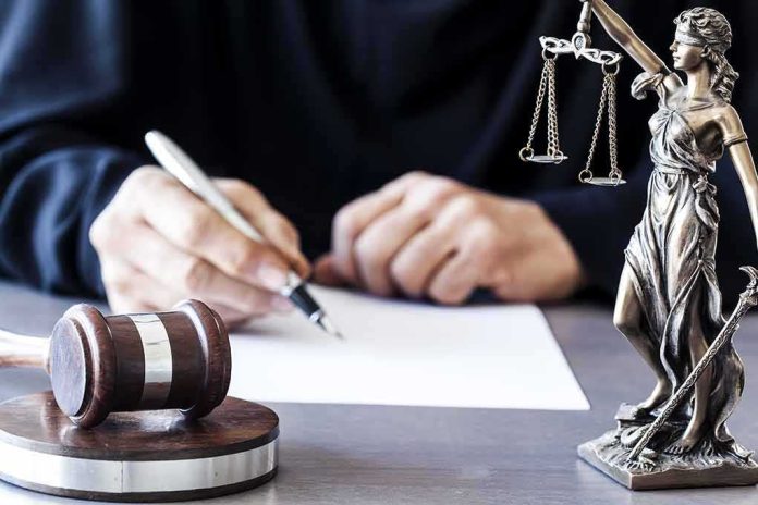 shutterstock_565403533-2 Judge writing at desk with gavel and Lady Justice statue