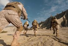 Soldiers in desert camouflage running across rocky terrain