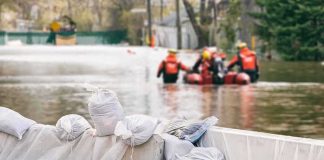 Devastating Nepal Floods: Leaving Hundreds Dead Sandbags stacked near a flooded street with rescue workers in a boat