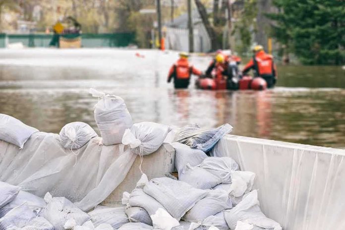Sandbags stacked near a flooded street with rescue workers in a boat