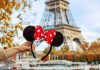 hand holding polka dot bow mouse ears in front of the Eiffel Tower