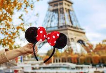 hand holding polka dot bow mouse ears in front of the Eiffel Tower