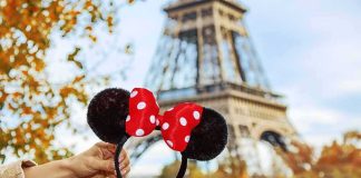 hand holding polka dot bow mouse ears in front of the Eiffel Tower
