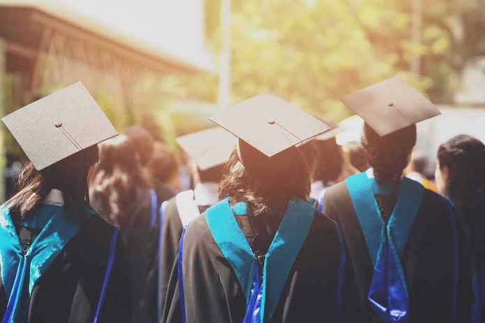 Graduates in caps and gowns walking at an outdoor ceremony