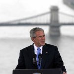 Shocking Move: Bush’s Message to Muslims George W. Bush speaking at a podium with a bridge over water in the background