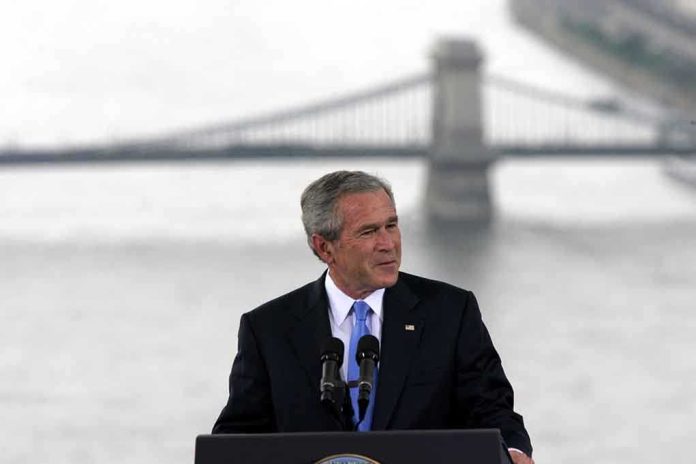 shutterstock_99420584-1 George W. Bush speaking at a podium with a bridge over water in the background