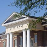 Mayor Denies Slur Allegation Exterior view of a city hall building with columns and a clear blue sky
