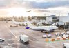 Airplanes at airport gates during sunset with ground vehicles and jet bridges