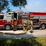 Heartwarming Cat Reunion Follows Apartment Fire Fire truck with firefighters operating hoses on a residential street