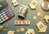 Rent payment concept with calculator, cash roll, coins, keys, and wooden house icons