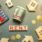 Parliament Blinks: Spain’s Housing Fight Escalates Rent payment concept with calculator, cash roll, coins, keys, and wooden house icons