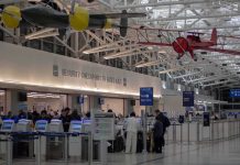 airport security checkpoint with passengers and hanging vintage airplanes