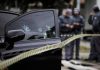 Car door with bullet holes at a taped-off crime scene