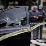 Federal Agents Fire at Fleeing Car Car door with bullet holes at a taped-off crime scene