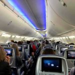 Tourist Seeks Proof Delta Warned Him Airplane cabin with passengers seated and seatback screens