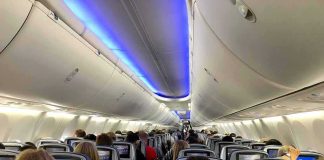Tourist Seeks Proof Delta Warned Him Airplane cabin with passengers seated and seatback screens