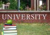 Stack of books with apple in front of university sign