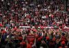 Speaker at podium addressing large crowd in arena
