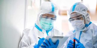 Mystery Pneumonia Death Raises Alarm Two healthcare workers in full PPE reviewing a clipboard