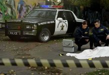 Crime scene with police car and two investigators by a covered body