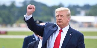 Trump Torches: North Carolina Rally Draws Thousands man in suit raising a clenched fist outdoors