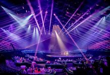 Concert stage with performers under purple laser lights