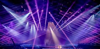 Concert stage with performers under purple laser lights