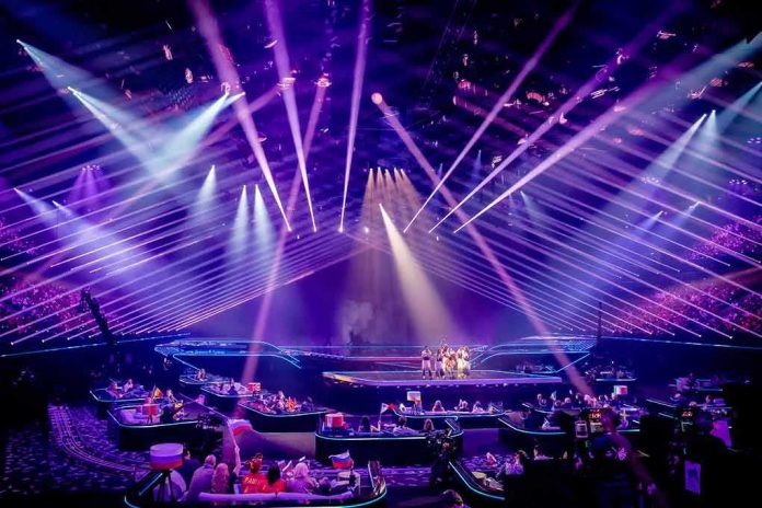 shutterstock_1982762090 Concert stage with performers under purple laser lights