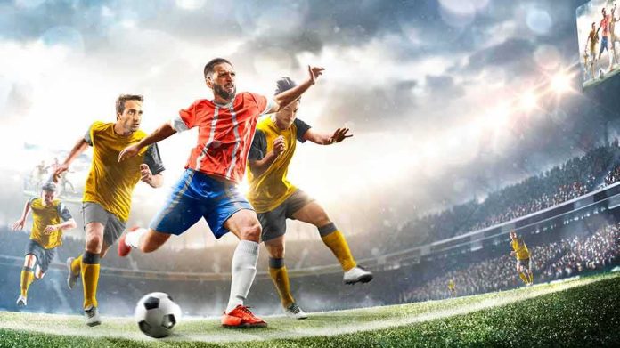shutterstock_1992389864 Soccer player in red jersey sprints past defenders in a stadium