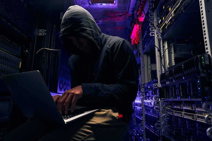 shutterstock_2067215408 Hooded person using a laptop in a dark server room