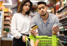 Couple with shopping cart checks credit card and phone