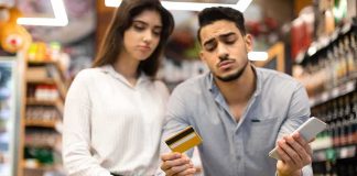 Couple with shopping cart checks credit card and phone