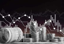 Stacks of coins and rolled dollar bills with falling financial charts