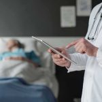 Police Probe 83-Year-Old Woman’s Assisted Death Doctor using tablet beside hospital patient